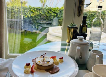 image of dessert plate next to restaurant window overlooking garden